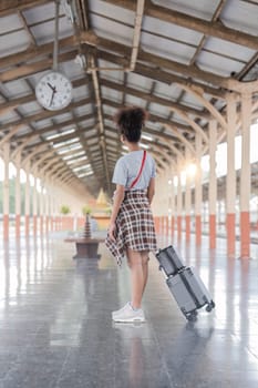 Young female traveler walking standing with a suitcase at train station. woman traveler tourist walking standing smiling with luggage at train station..