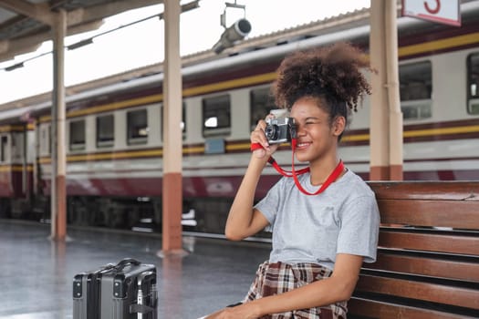 Young Asian African woman traveler with backpack in the railway train station, traveler girl walking stand sit waiting take a picture on railway platform train station. High quality photo..