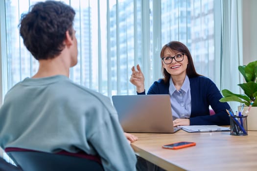 Guy student 18, 19 years old at therapy meeting with psychologist, social worker, mentor in college office. Social life, mental health, psychology, youth concept