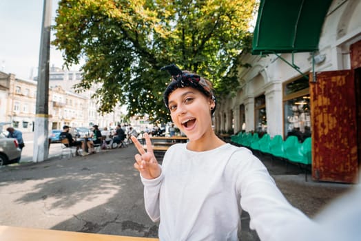 Close up portrait of a girl showing v-sign wear white t-shirt outdoor