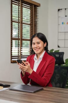 Beautiful business asian woman with working office desk using phone and computer laptop.