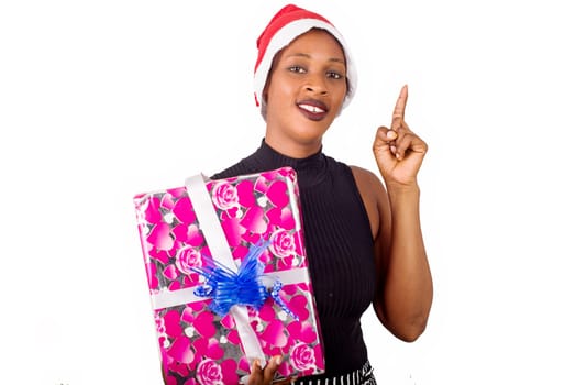young woman standing in a hat looking at the camera smiling with a package in hand.
