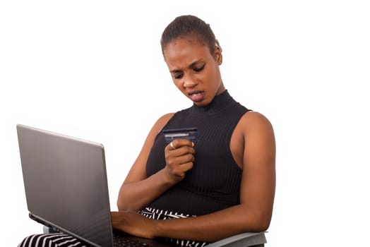 shocked businesswoman is looking at her credit card about to make online shopping with credit card using laptop in the office,