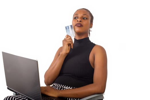 young woman sitting with laptop and credit card thinking.