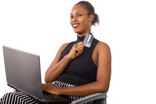 young woman sitting with laptop and credit card smiling.