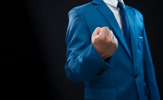 Businessman in blue suit and showing fist on a fresh background.