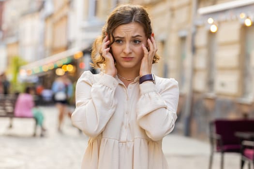 Sad unhappy pretty young woman thinks over life concerns, suffers from unfair situation. Problem, feeling bad, annoyed, burnout, grief. Frustrated depressed lonely girl tourist walking in city street