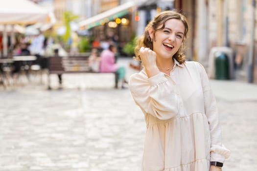 Portrait of young woman shouting, celebrating success, winning, goal achievement, good news, lottery jackpot luck, victory outdoors. Lovely pretty girl walking in urban city street. Town lifestyles