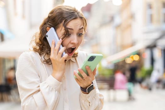Irritated nervous stressed young woman talking screaming on two mobile phones having conversation conflict quarrel complaint dispute discuss solve problem outdoors. Girl walking in urban city street