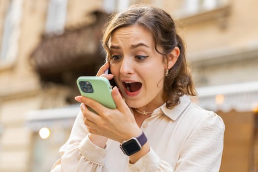 Irritated nervous stressed young woman talking screaming on two mobile phones having conversation conflict quarrel complaint dispute discuss solve problem outdoors. Girl walking in urban city street
