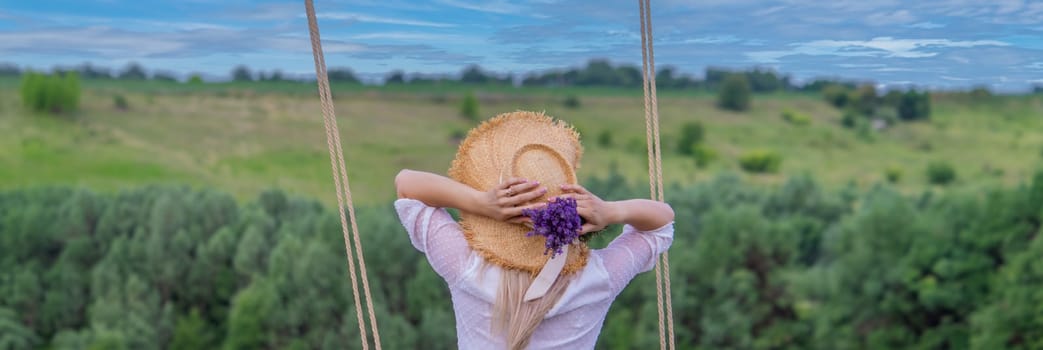 girl on a swing in a field of lavender. Selective focus. Nature