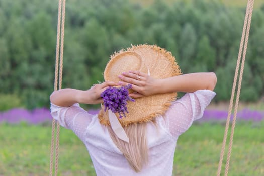 girl on a swing in a field of lavender. Selective focus. Nature