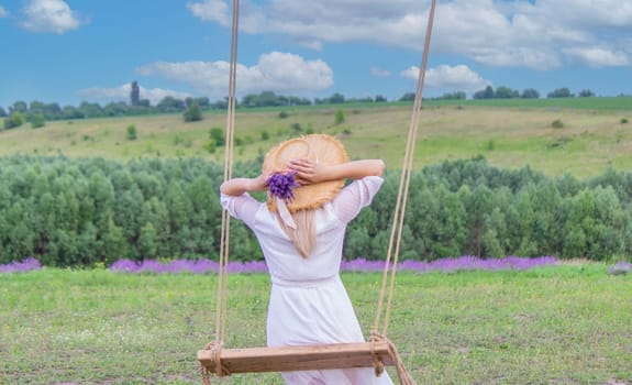 girl on a swing in a field of lavender. Selective focus. Nature