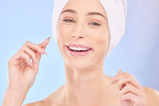 Flossing, teeth and woman in portrait, dental and health with oral care isolated on blue background. Female model, morning routine and orthodontics, hygiene and cleaning mouth with thread in studio.