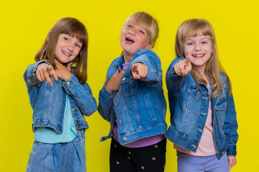 Teenage girls laughing out loud after hearing ridiculous anecdote, funny joke, feeling carefree amused, positive people lifestyle. Little children sisters. Three siblings kids on yellow background