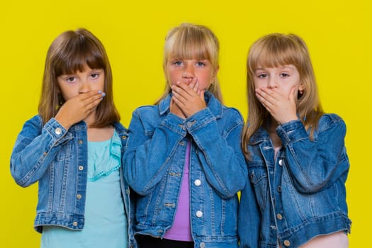 I will not say anyone. Little girls closing mouth with hands, looking intimidated scared at camera, gestures no, refusing to tell terrible secret, unbelievable truth. Three children siblings kids