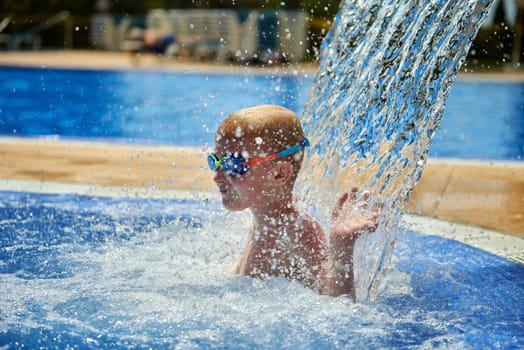 Young boy kid child eight years old splashing in swimming pool having fun leisure activity. Boy happy swimming in a pool. Activities on the pool, children swimming and playing in water, happiness and summertime