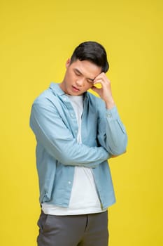 Young handsome holding his head looking desperate isolated on yellow background