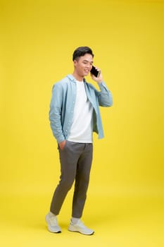 Happy smiling man in jeans and denim shirt talking on the phone looking at camera. 