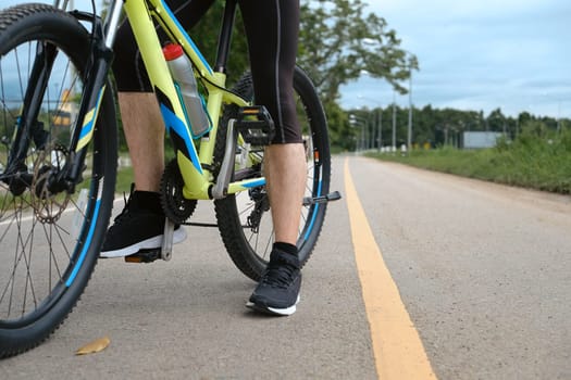 Cropped image of sporty man riding a bicycle on country road. Travel, sport and active lifestyle concept.
