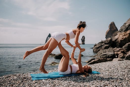 Woman sea yoga. Back view of free calm happy satisfied woman with long hair standing on top rock with yoga position against of sky by the sea. Healthy lifestyle outdoors in nature, fitness concept.