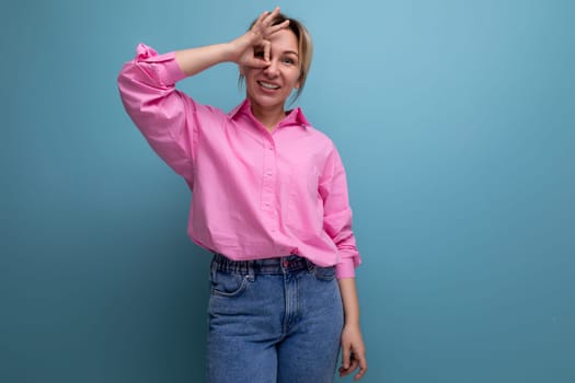 young smiling european blond office worker woman dressed in a pink shirt and jeans.
