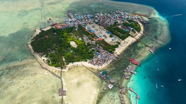 Aerial view of tropical island Mabul in the blue sea with a coral reef and the beach. Semporna, Sabah, Malaysia.