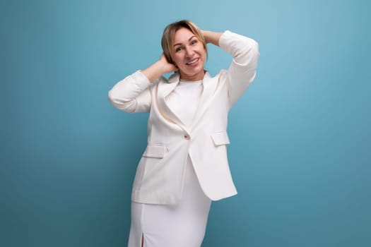 young slim blond business woman in a white elegant jacket and skirt on a blue background with copy space.