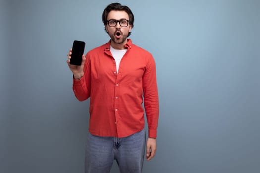 handsome surprised dark-haired 30s man in red shirt holding phone.