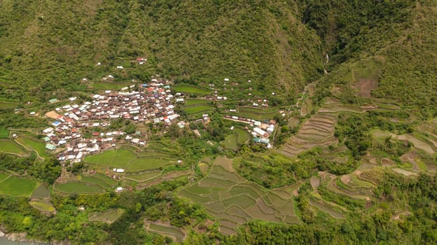 Aerial view of village among rice terraces and fields in the mountains. Philippines, Luzon.