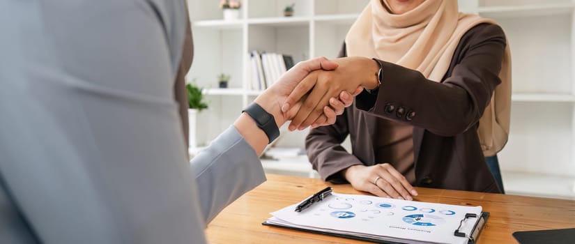 Two hijab Asian women shaking hands after a startup company meeting. run by a young, talented woman. The management concept runs the company to grow the company.