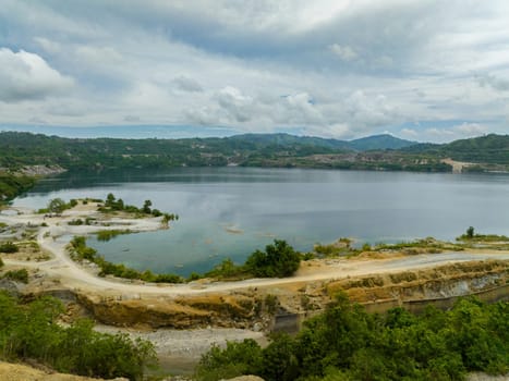 Mining quarry with flooded bottom. Lake with blue water near sand pit. Sipalay, Negros, Philippines.