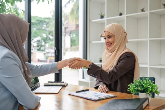 Two hijab Asian women shaking hands after a startup company meeting. run by a young, talented woman. The management concept runs the company to grow the company.