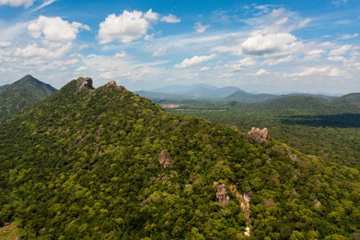Top view of mountains covered with green forest and valley with jungle against blue sky and clouds. Sri Lanka.