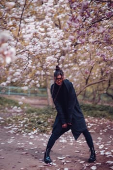 Beautiful dramatic young woman wearing black kimono and yellow glasses with cherry blossoms, sakura view. High quality photo