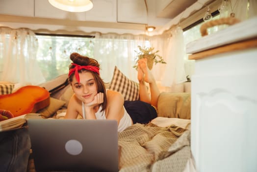 Portrait of a cute lesbian couple. Two girls spend time tenderly together watching movie on laptop in a camper trailer with LGBT flag on the wall. Love and attitude. LGBT concept. High quality photo