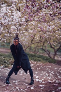 Beautiful dramatic young woman wearing black kimono and yellow glasses with cherry blossoms, sakura view. High quality photo