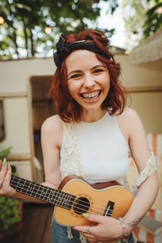 Happy hippie girl are having a good time with playing on guitar in camper trailer. Holiday, vacation, trip concept.High quality photo