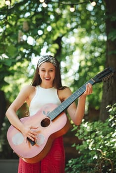 Happy hippie girl is having a good time with playing on guitar in camper trailer. Holiday, vacation, trip concept.High quality photo