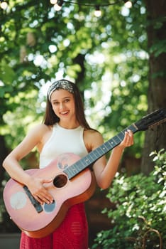 Happy hippie girl is having a good time with playing on guitar in camper trailer. Holiday, vacation, trip concept.High quality photo