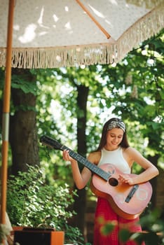 Happy hippie girl is having a good time with playing on guitar in camper trailer. Holiday, vacation, trip concept.High quality photo