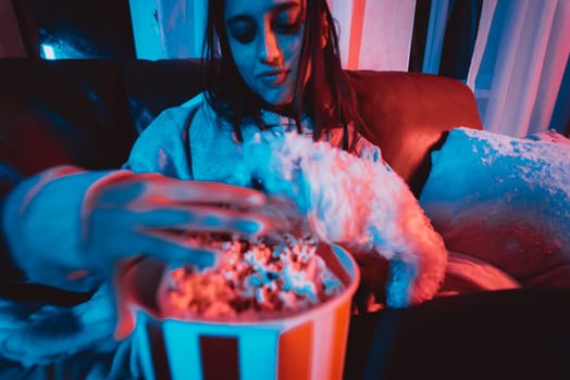 Close up portrait of Beautiful young girl at home in a dark room with a popcorn bucket playing with her dog and sits in front of a monitor or TV watching movie. Crazy emotions. High quality photo
