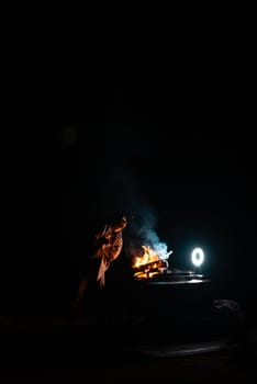 Man preparing bbq grill to cook on fire. Outside dark shot. Freeze moment of fire. High quality photo