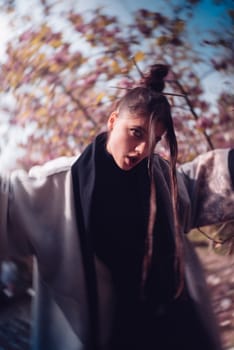 Beautiful dramatic young woman wearing kimono with cherry blossoms, sakura view. High quality photo