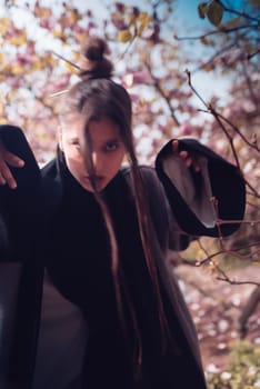 Beautiful dramatic young woman wearing kimono with cherry blossoms, sakura view. High quality photo
