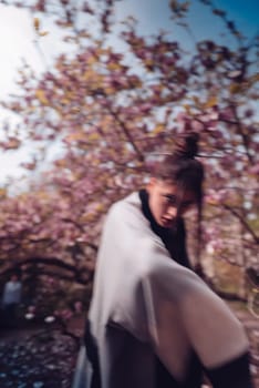 Beautiful dramatic young woman wearing kimono with cherry blossoms, sakura view. High quality photo