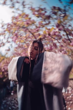Beautiful dramatic young woman wearing kimono with cherry blossoms, sakura view. High quality photo