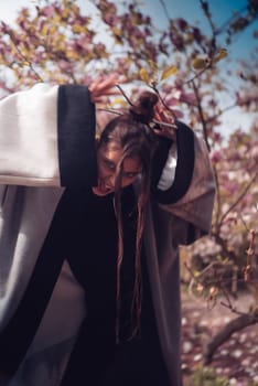 Beautiful dramatic young woman wearing kimono with cherry blossoms, sakura view. High quality photo