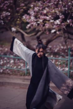 Beautiful dramatic young woman wearing kimono with cherry blossoms, sakura view. High quality photo