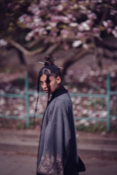 Beautiful dramatic young woman wearing kimono with cherry blossoms, sakura view. High quality photo